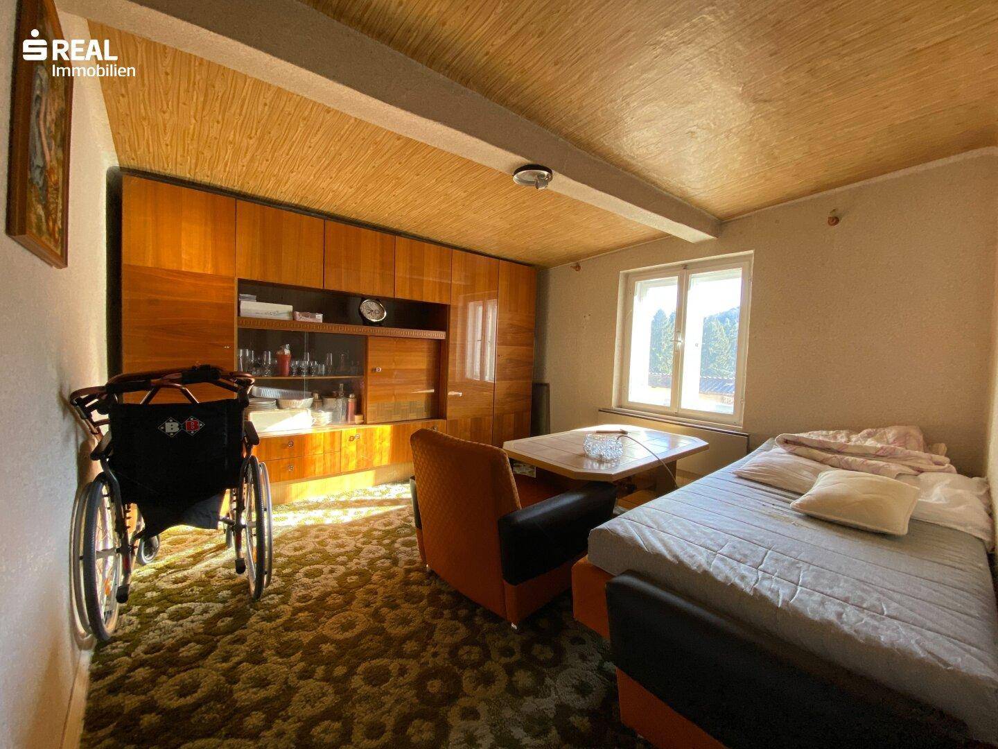 Gemütliches Schlafzimmer mit Holzdecke, Teppichboden und großem Wandschrank.