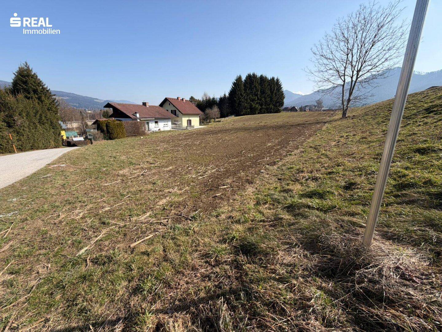 Sonnenverwöhntes Grundstück mit weitem Blick auf die Alpen und angrenzende Bebauung.