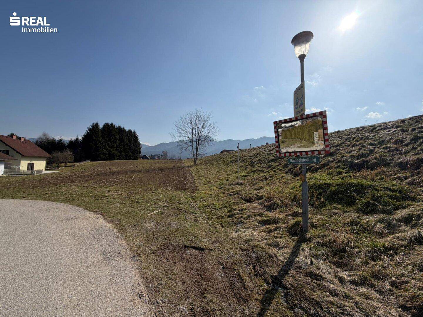 Zufahrtsstraße zum Grundstück mit Straßenlaterne und Weitblick auf die Landschaft.