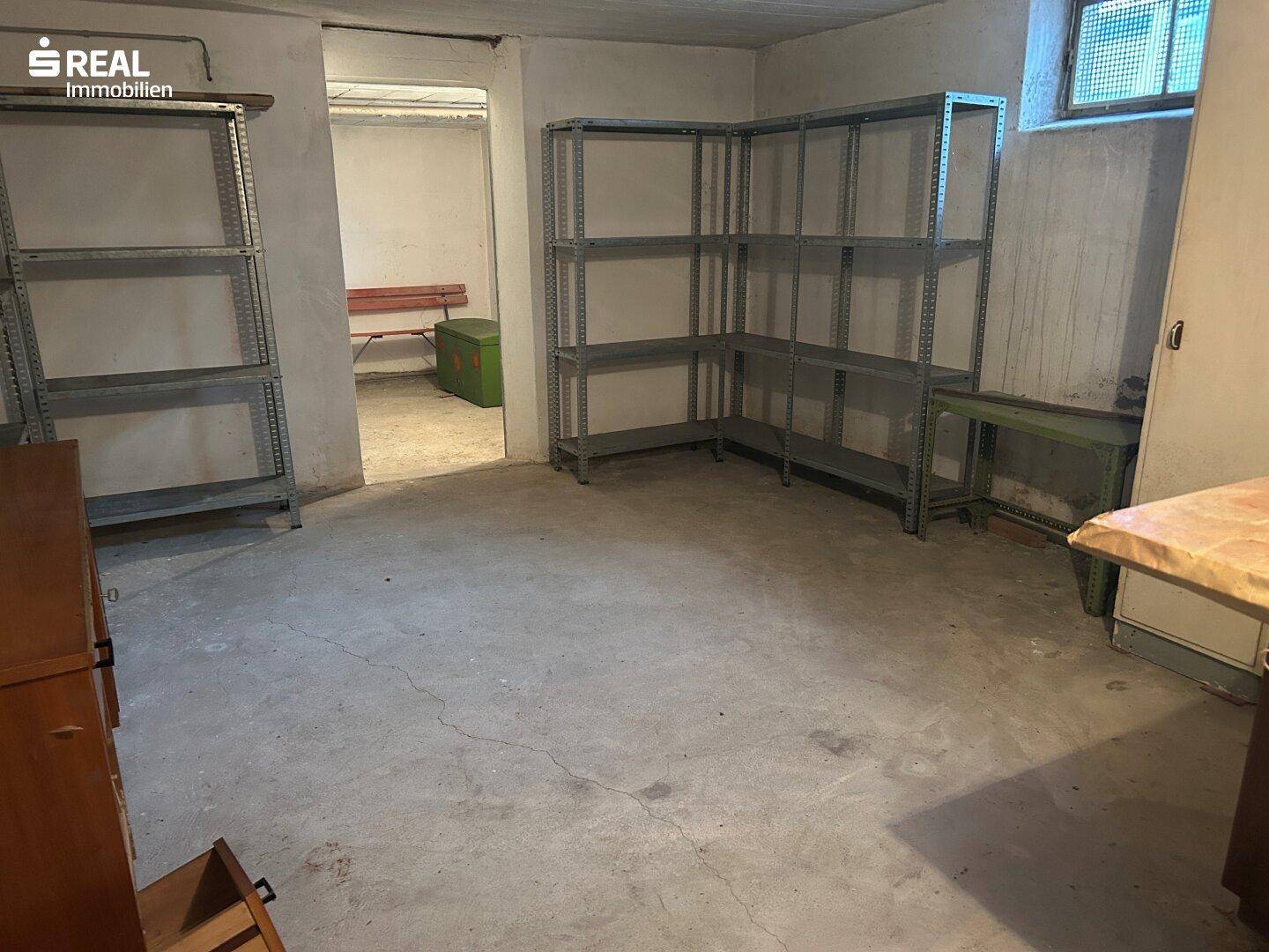 Geräumiger Kellerraum mit Regalen und Betonboden für Lagerzwecke.