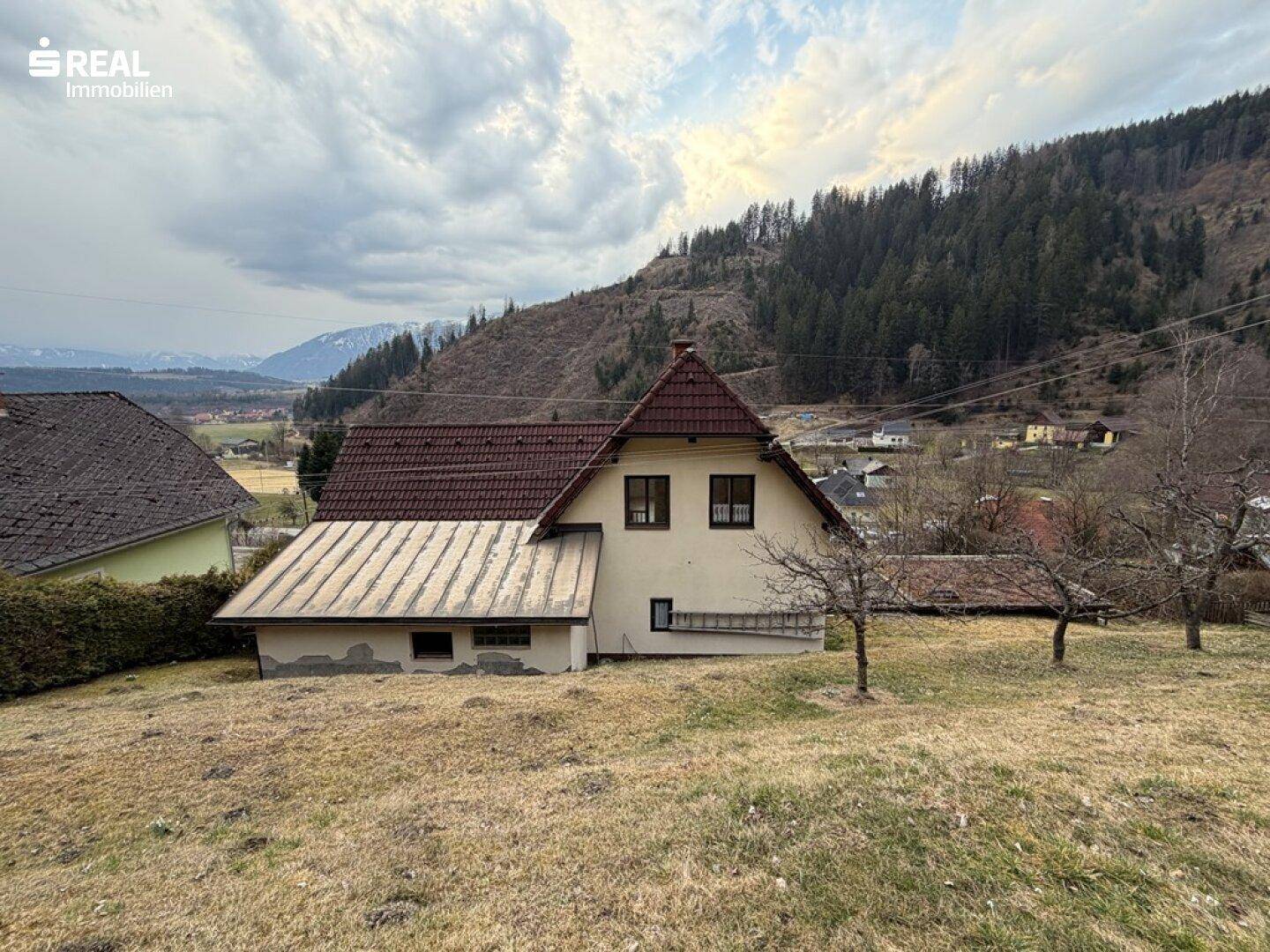 Rückansicht des Hauses mit Satteldach und weitem Blick auf die umliegende Berglandschaft.