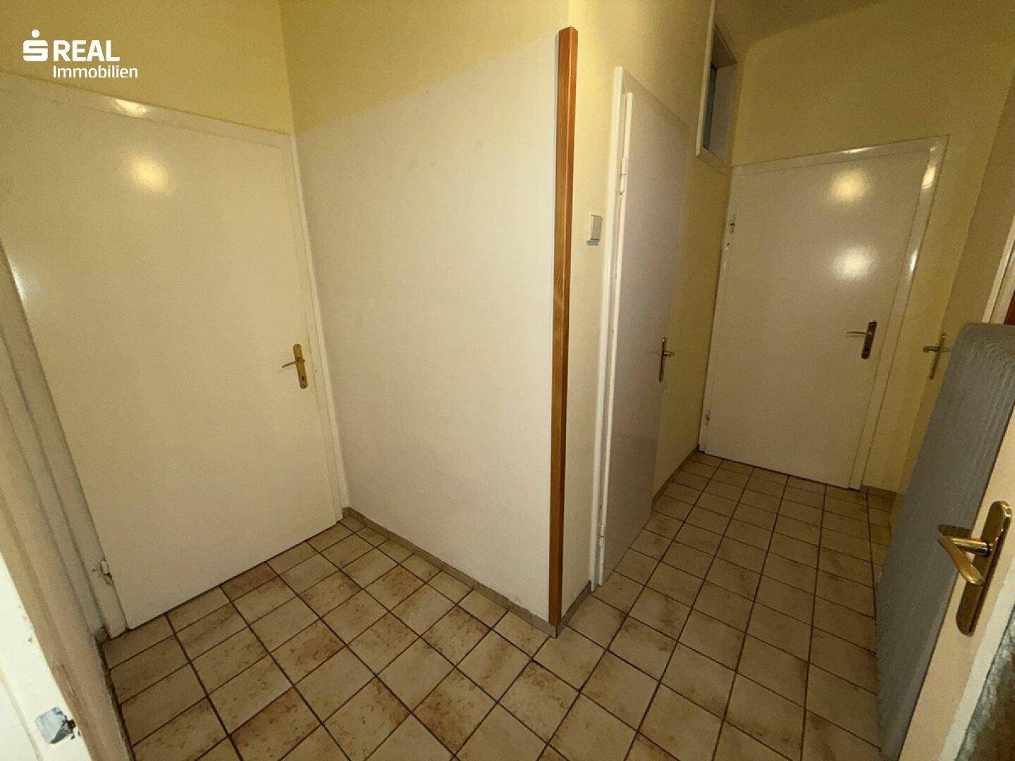 Heller Flur mit Fliesenboden und mehreren Türen, der verschiedene Räume verbindet.