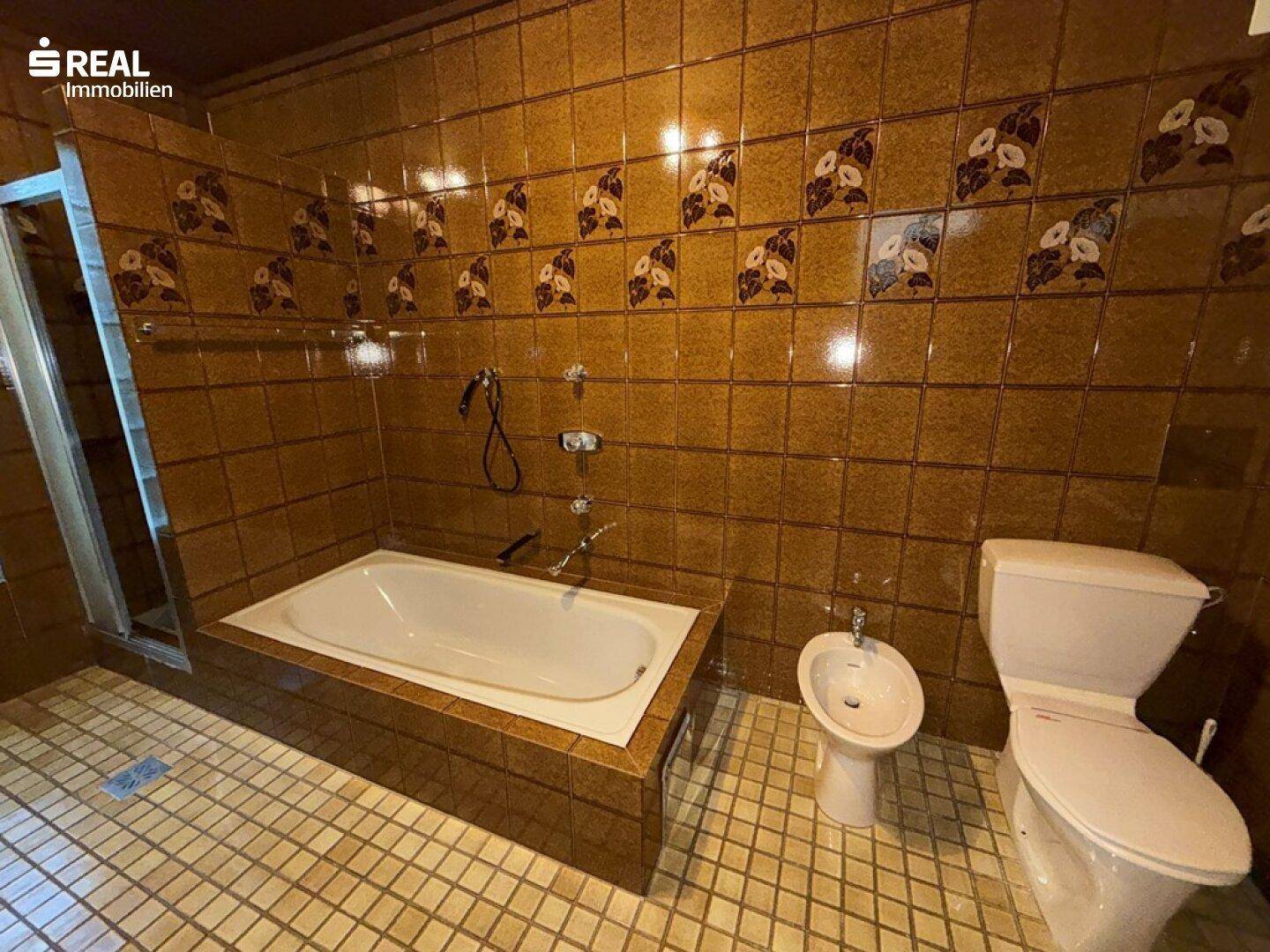 Badezimmer mit braunen Fliesen, Badewanne, Bidet und Toilette, ausgestattet für den täglichen Gebrauch.