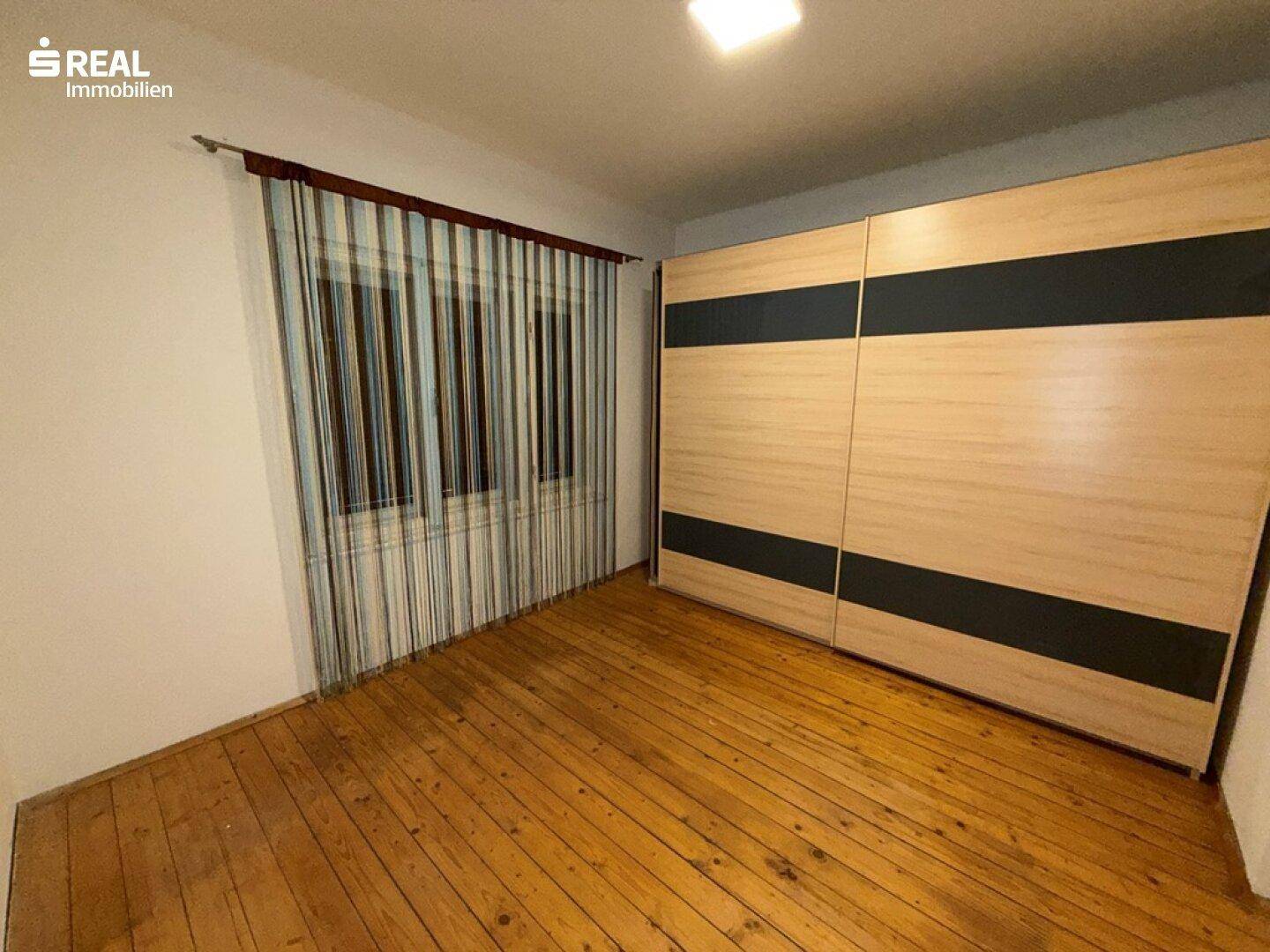 Schlafzimmer mit Holzdielenboden und großem Schiebetürenschrank, bietet viel Stauraum.