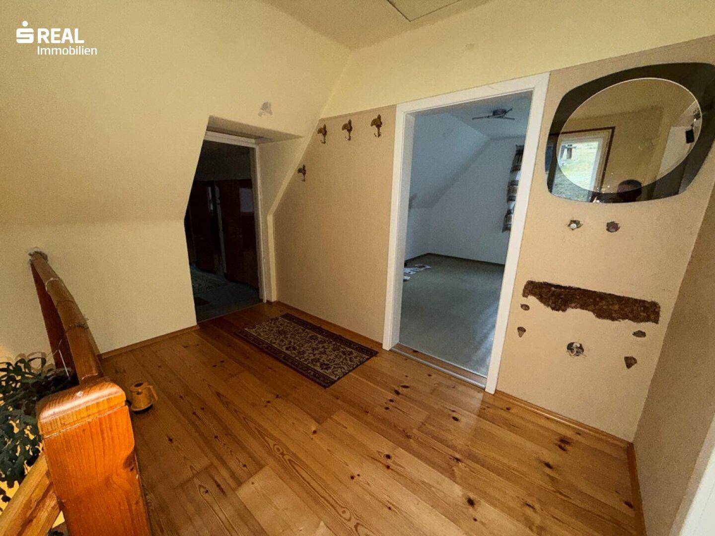 Heller Flur im Obergeschoss mit Holzdielenboden und Zugang zu weiteren Zimmern.