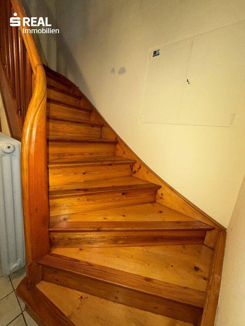 Holztreppe mit Geländer, die die verschiedenen Etagen des Hauses miteinander verbindet.