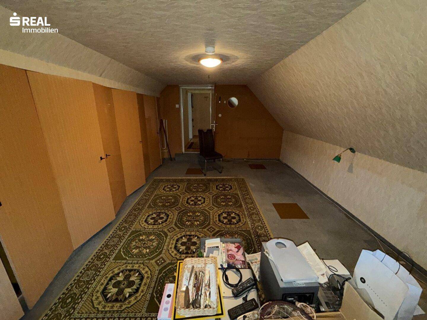 Geräumiges Dachzimmer mit Teppichboden und Einbauschränken, ideal für Lagerung oder Hobby.