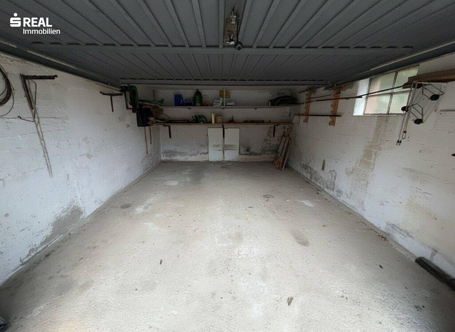 Leere Garage mit Betonboden und Fenster, bietet Platz für ein Fahrzeug und Lagerung.