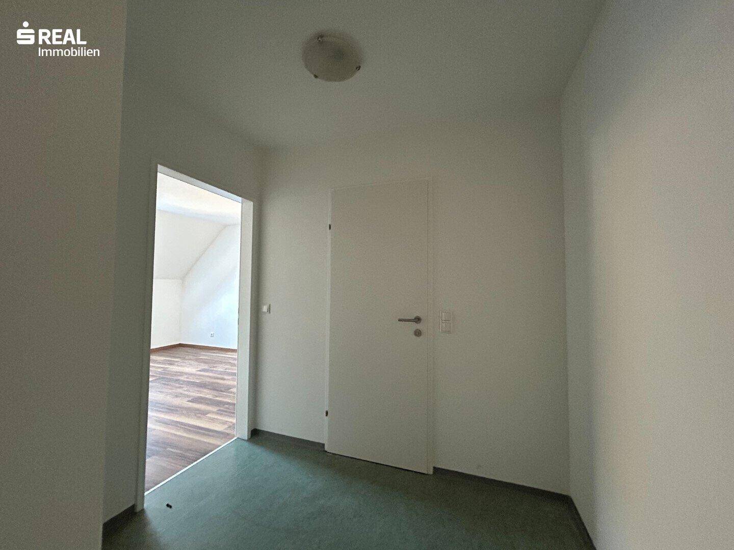 Flur mit grünem Bodenbelag und Zugang zu weiteren Zimmern im Dachgeschoss.