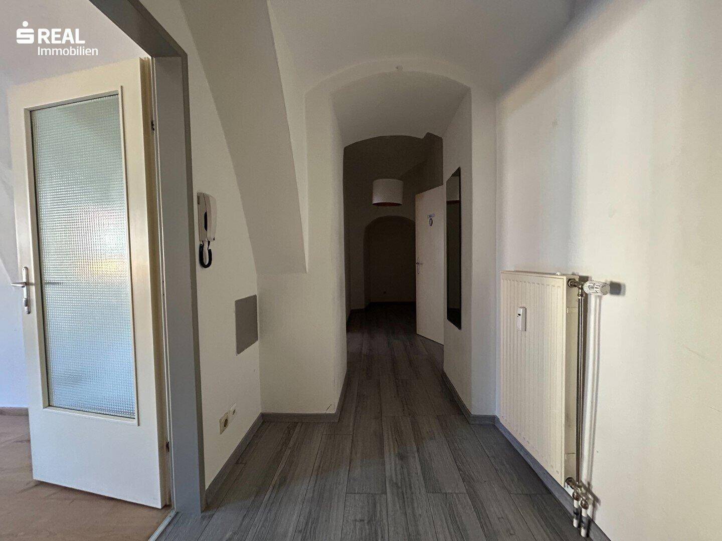 Langer Flur mit Laminatboden und Zugang zu weiteren Räumen.