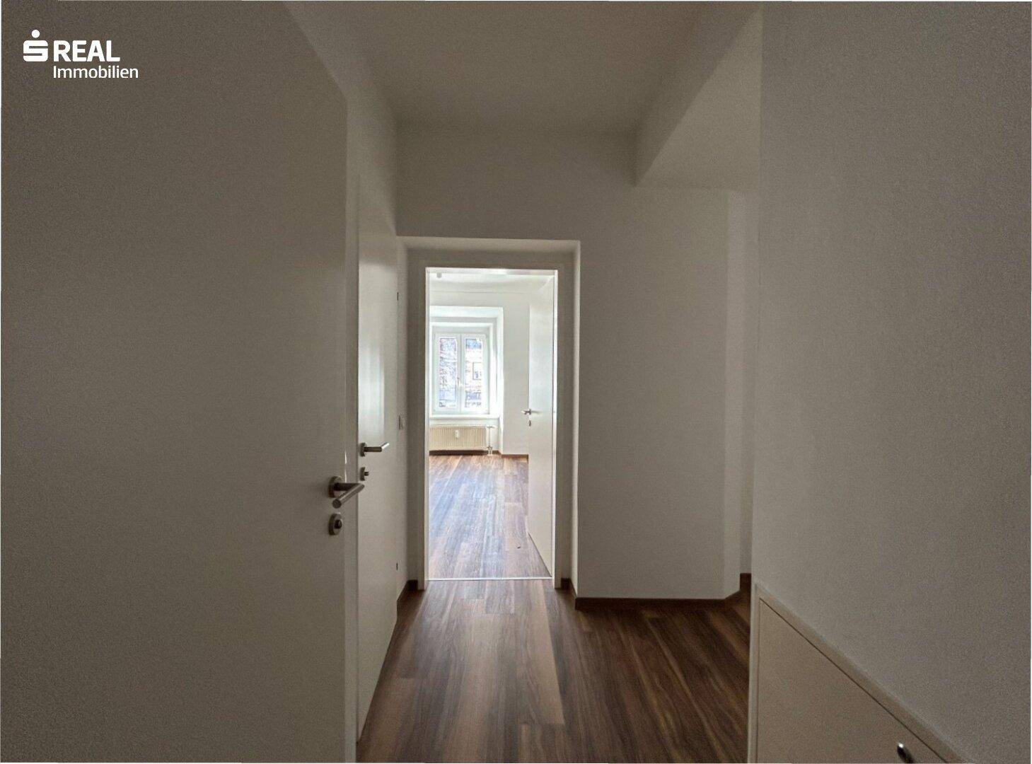Heller Flur mit Laminatboden, der zu weiteren Wohnbereichen führt.