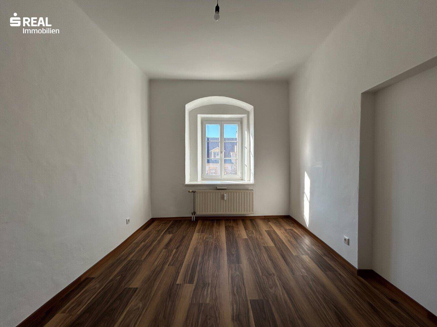 Heller Flur mit grünem Bodenbelag und Zugang zu einem weiteren Raum.