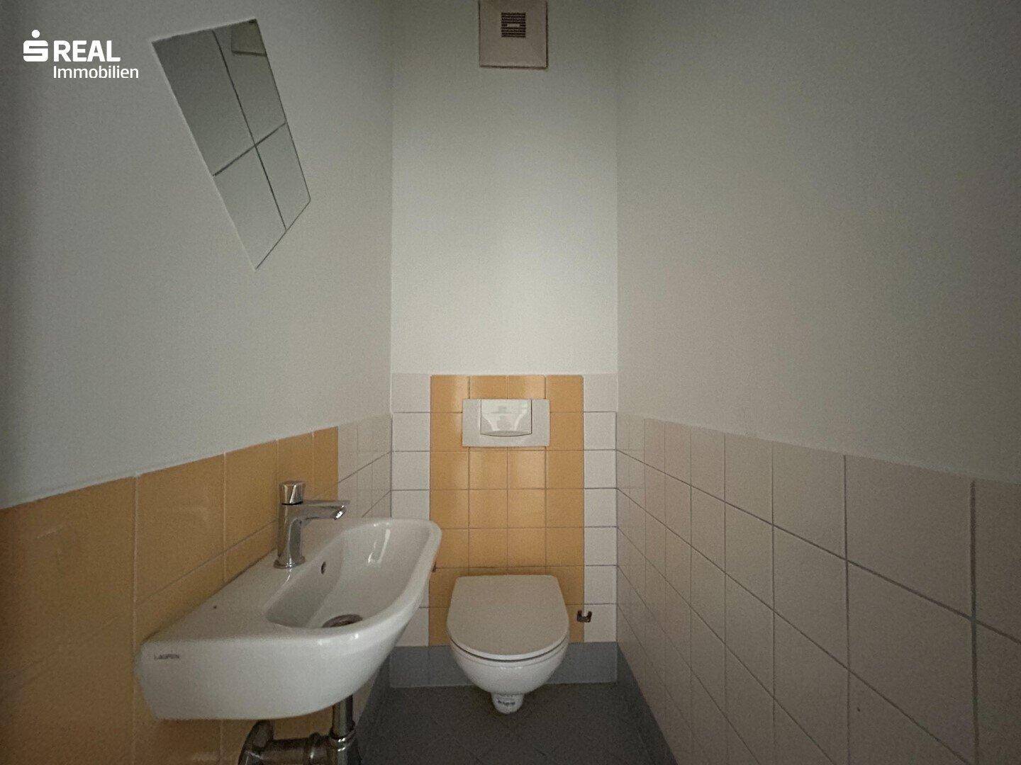 Funktionale Küche mit hellen Schränken, Holz-Arbeitsplatte und Elektroherd.
