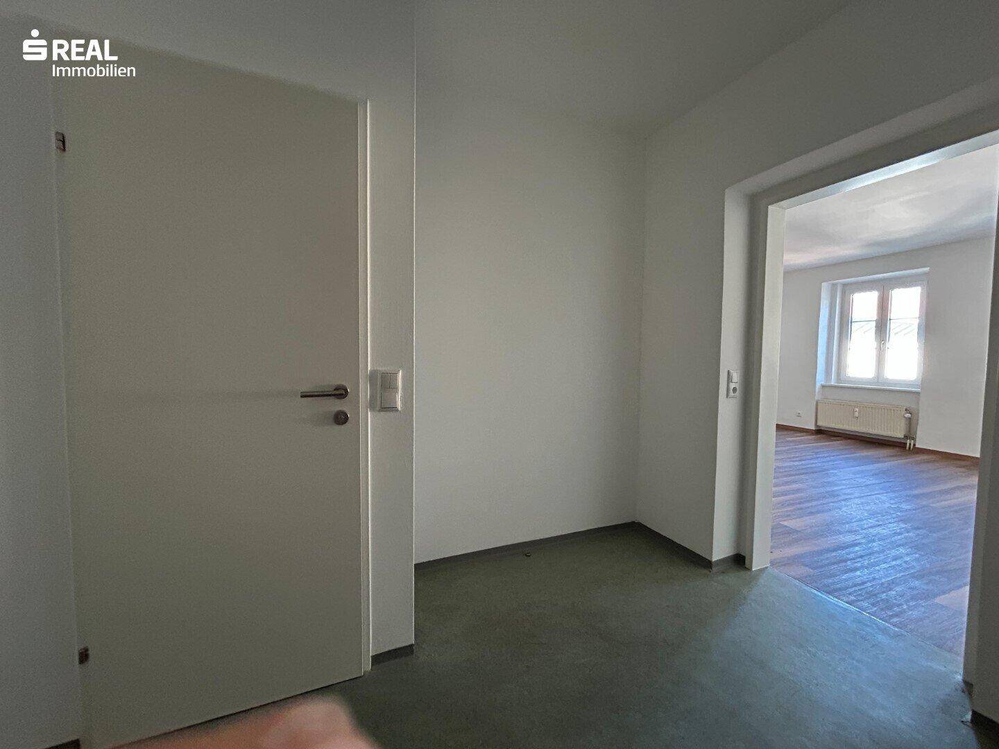 Flur im Dachgeschoss mit Zugang zu zwei hellen Zimmern mit Dachfenstern.
