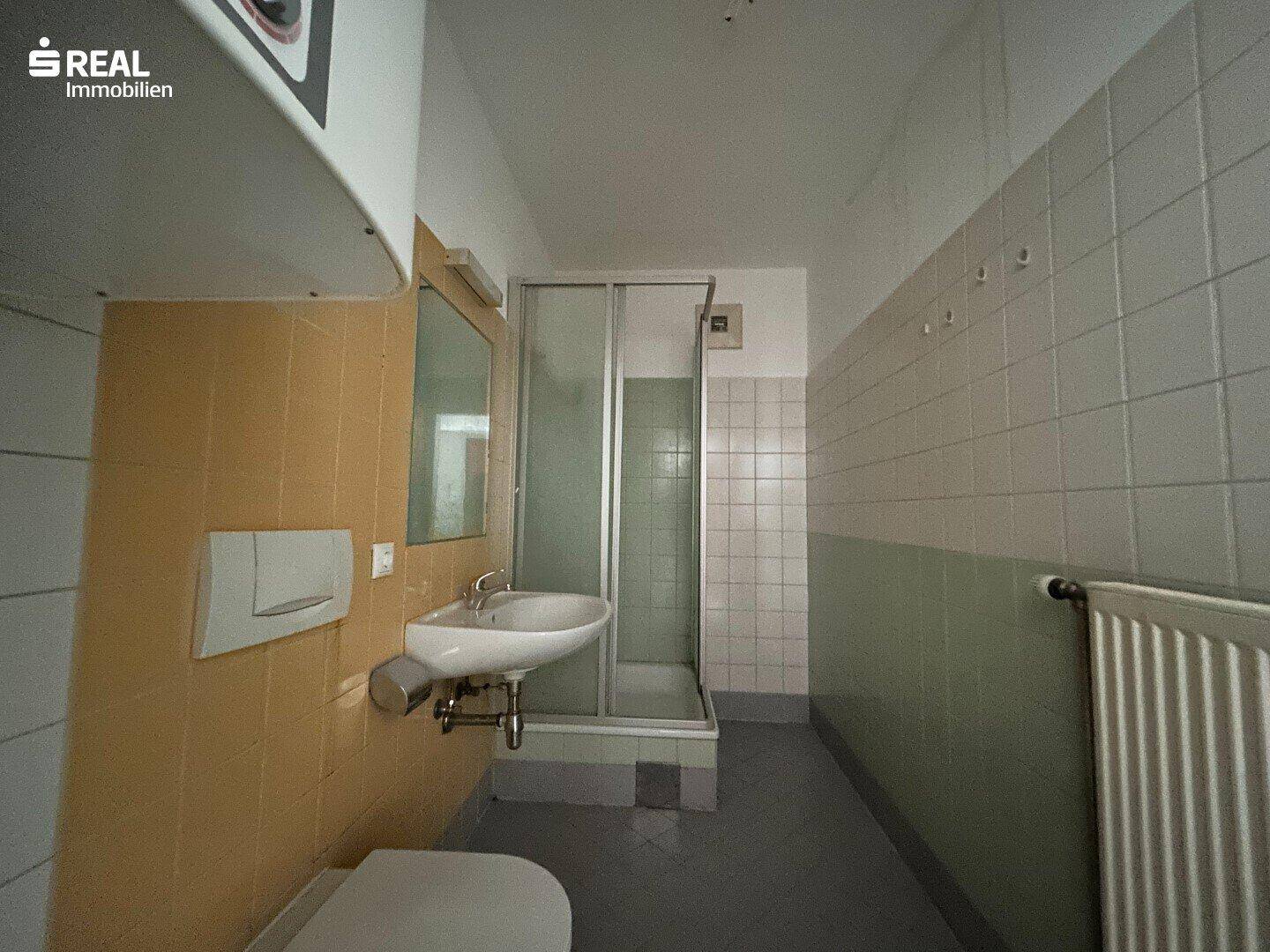 Badezimmer mit Duschkabine, Waschbecken und Spiegelschrank in älterem Stil.