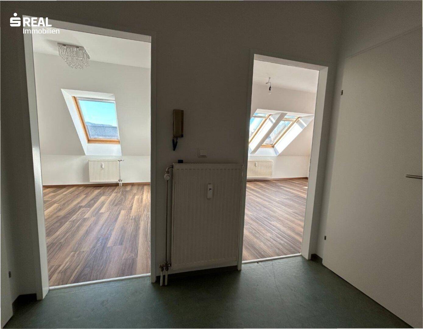 Flur mit Zugang zu mehreren Räumen, darunter die hellen Dachbodenbereiche mit Laminatboden.