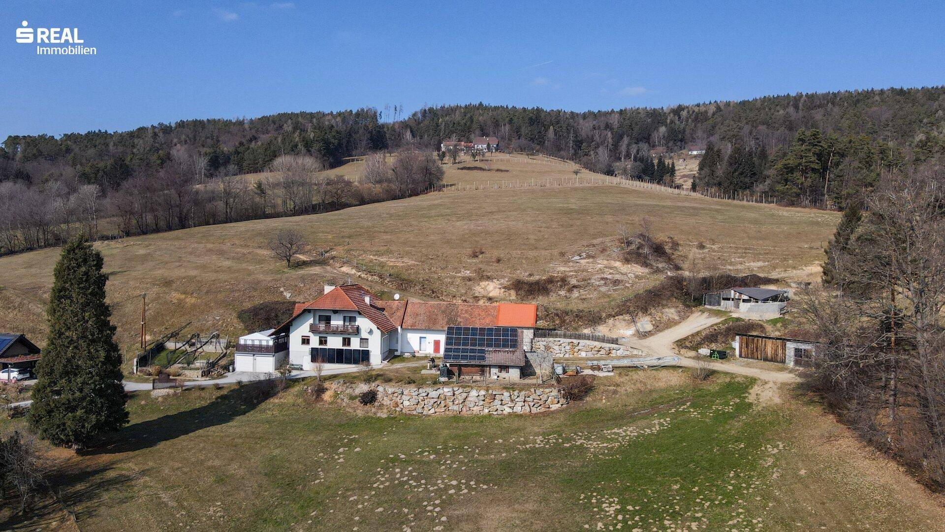 Luftaufnahme des Anwesens mit Haupthaus, Nebengebäuden und weitläufiger Grünfläche.