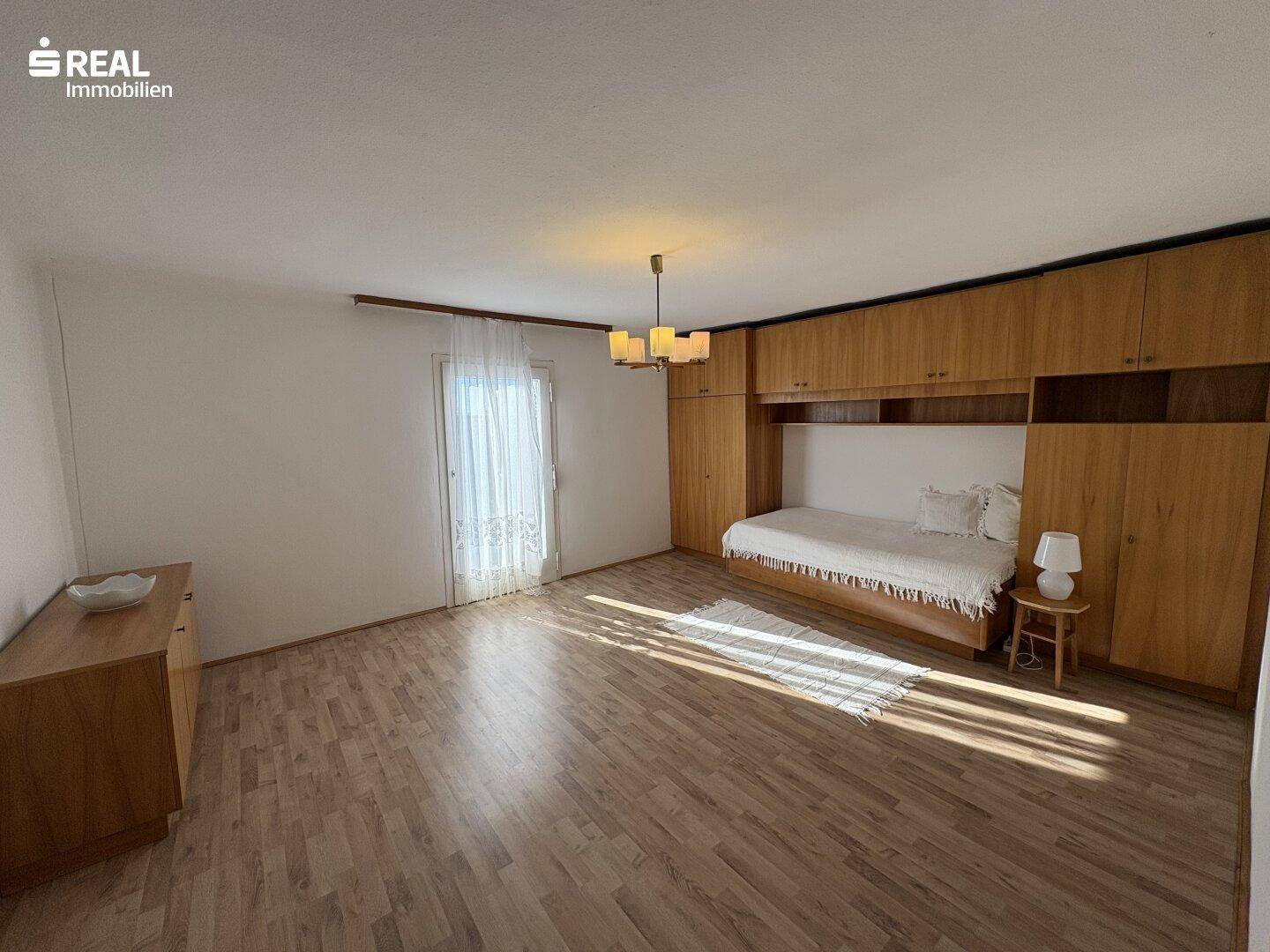 Schlafzimmer mit Einbauschränken aus Holz und Laminatboden, hell und funktional eingerichtet.