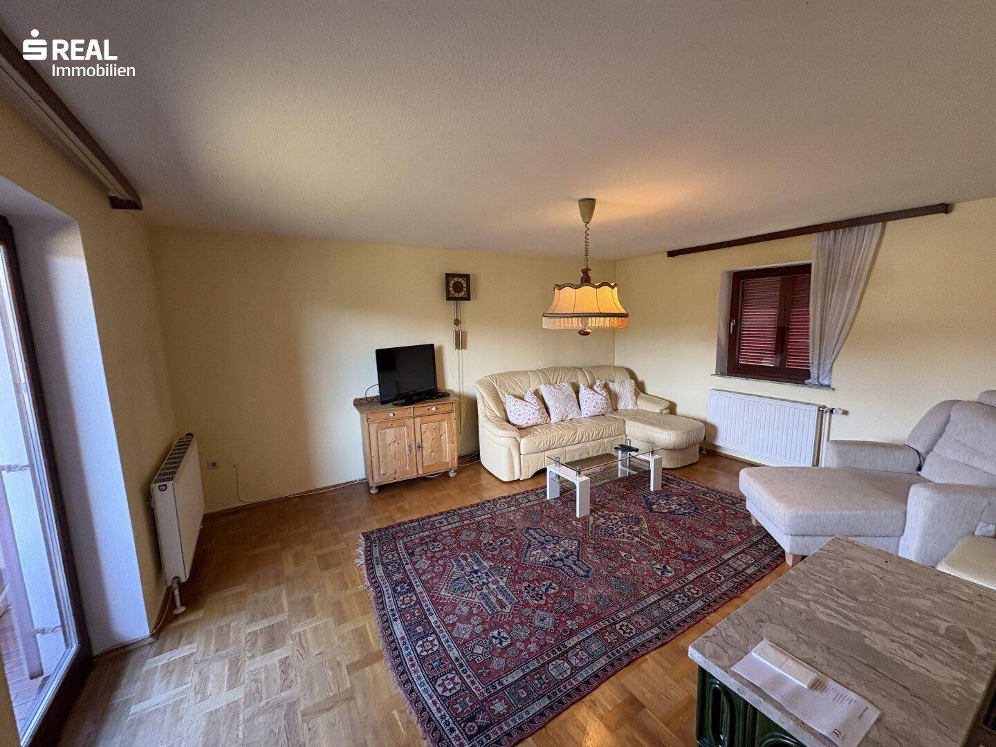Gemütliches Wohnzimmer mit Sofa, Teppich und Laminatboden, einladend und hell.