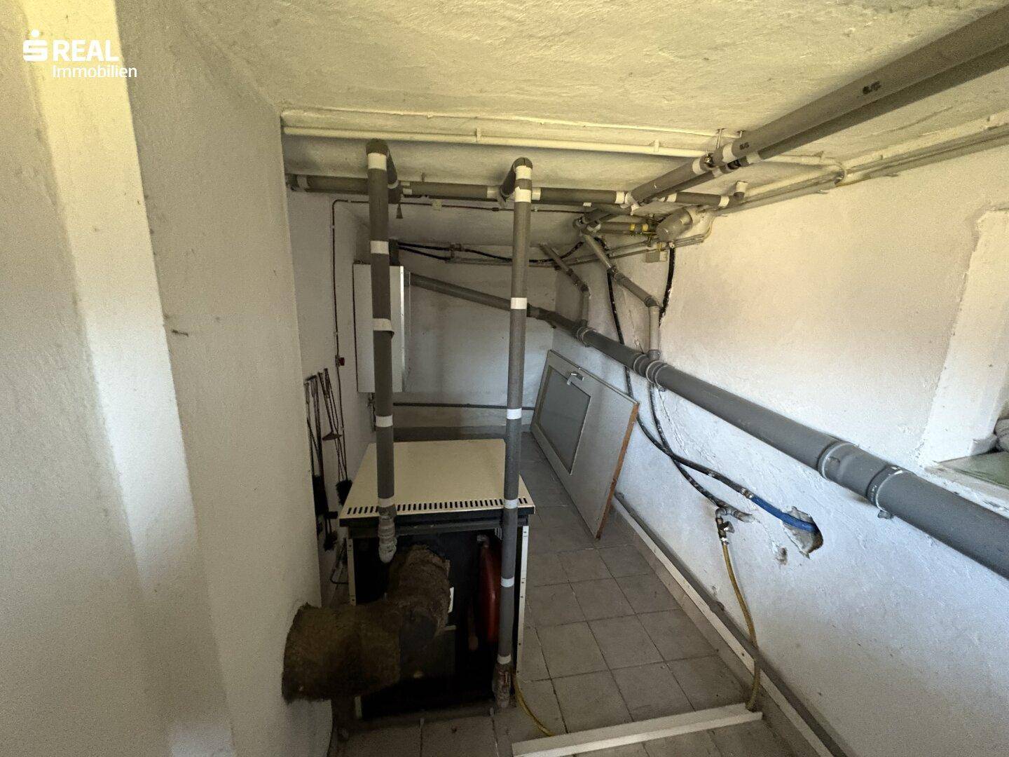 Heizungsraum im Keller mit Rohren und technischer Ausstattung, funktional und aufgeräumt.