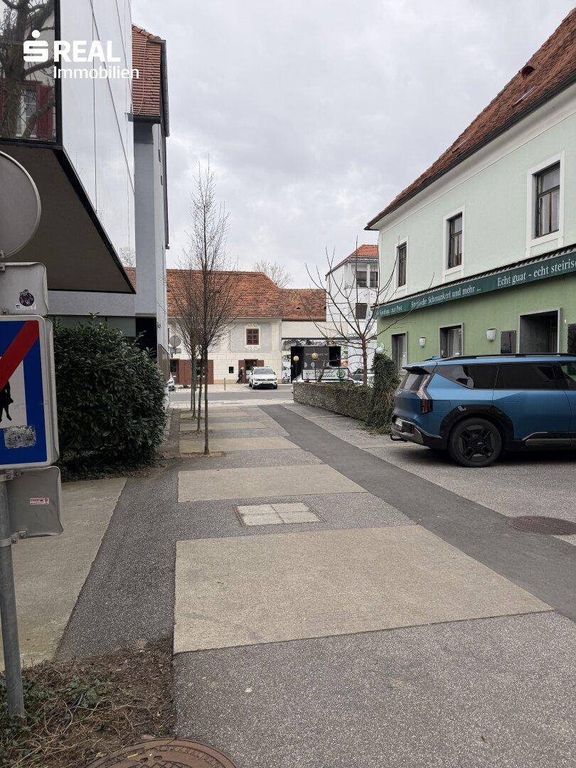 Blick auf eine ruhige Straße mit geparkten Autos und traditionellen Gebäuden in der Umgebung.