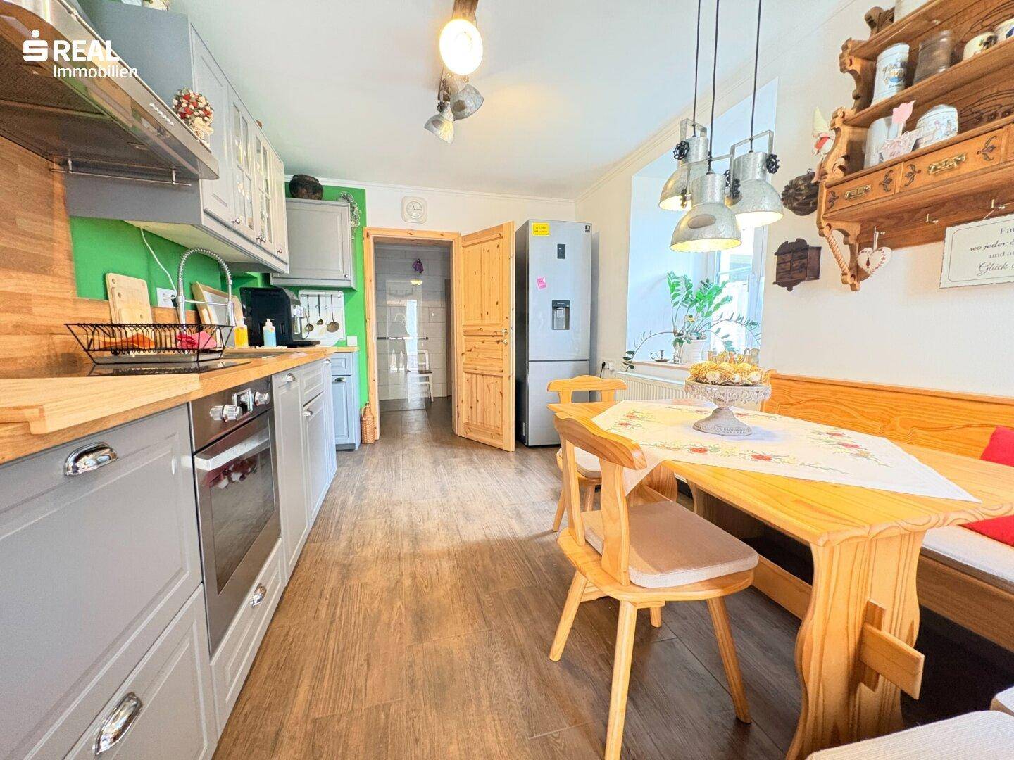 Gemütliche Wohnküche mit Holzboden, grauen Schränken und einem Essbereich mit Eckbank.
