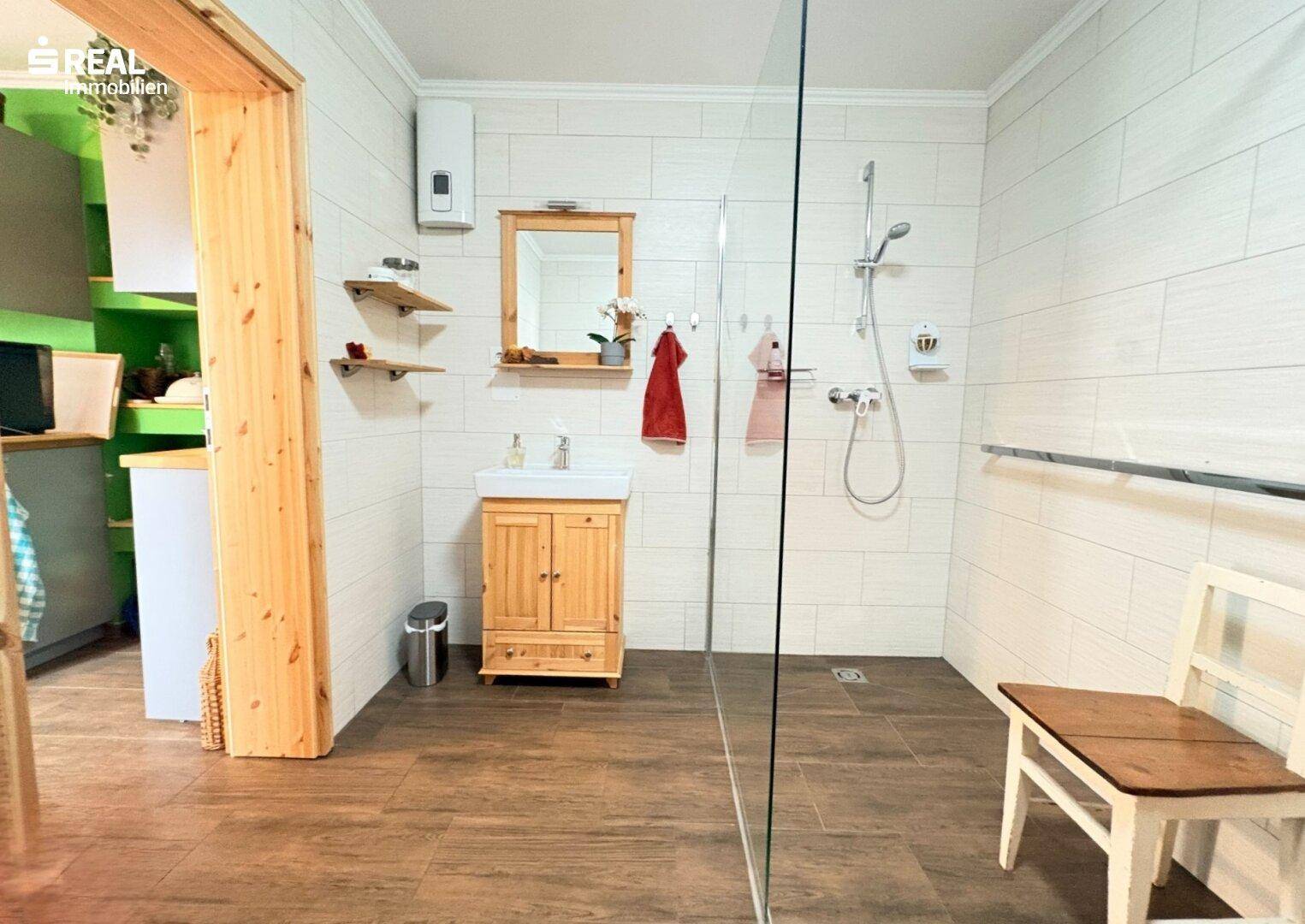 Modernes Badezimmer mit ebenerdiger Dusche, Holzwaschtisch und hellen Fliesen.