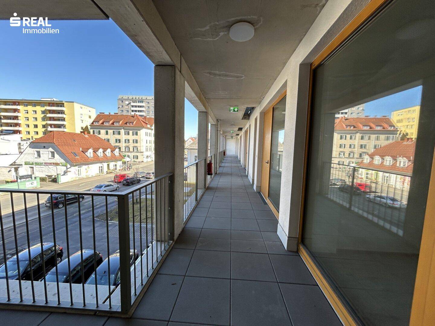 Langer Laubengang mit Blick auf die Straße und angrenzende Gebäude.
