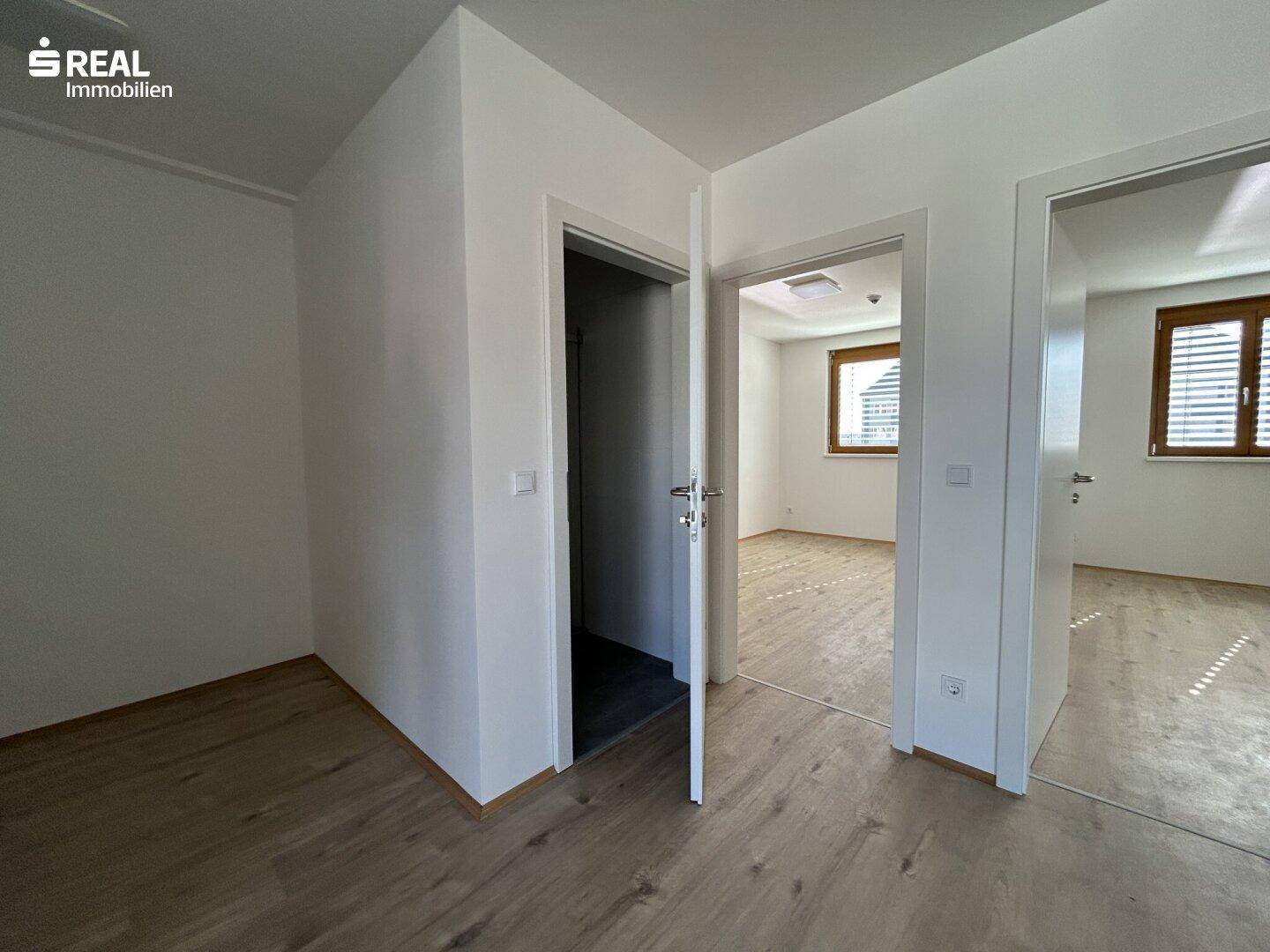 Zentraler Raum mit Laminatboden und offenen Türen zu angrenzenden Zimmern.