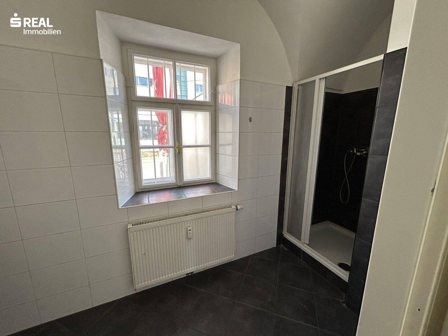Badezimmer mit Duschkabine, Fenster und charakteristischer Gewölbedecke.