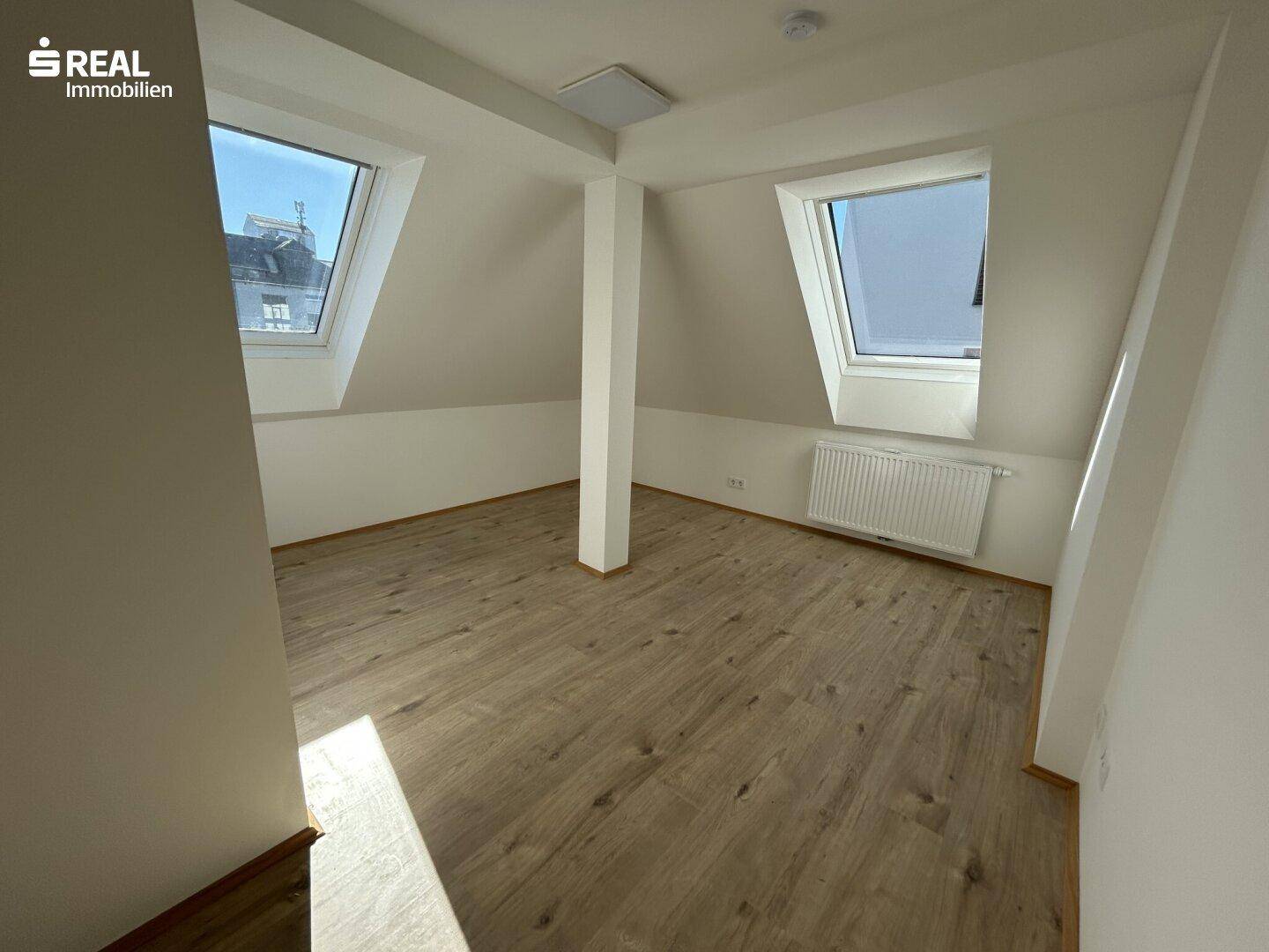 Geräumiges Dachgeschosszimmer mit Laminatboden, Dachschrägen und zwei Dachfenstern.