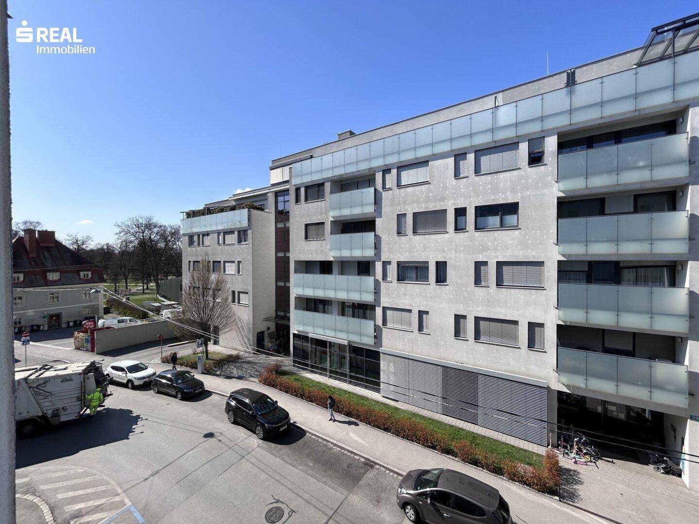 Moderne Wohnanlage mit mehreren Etagen, Balkonen und Blick auf die Straße und umliegende Gebäude.