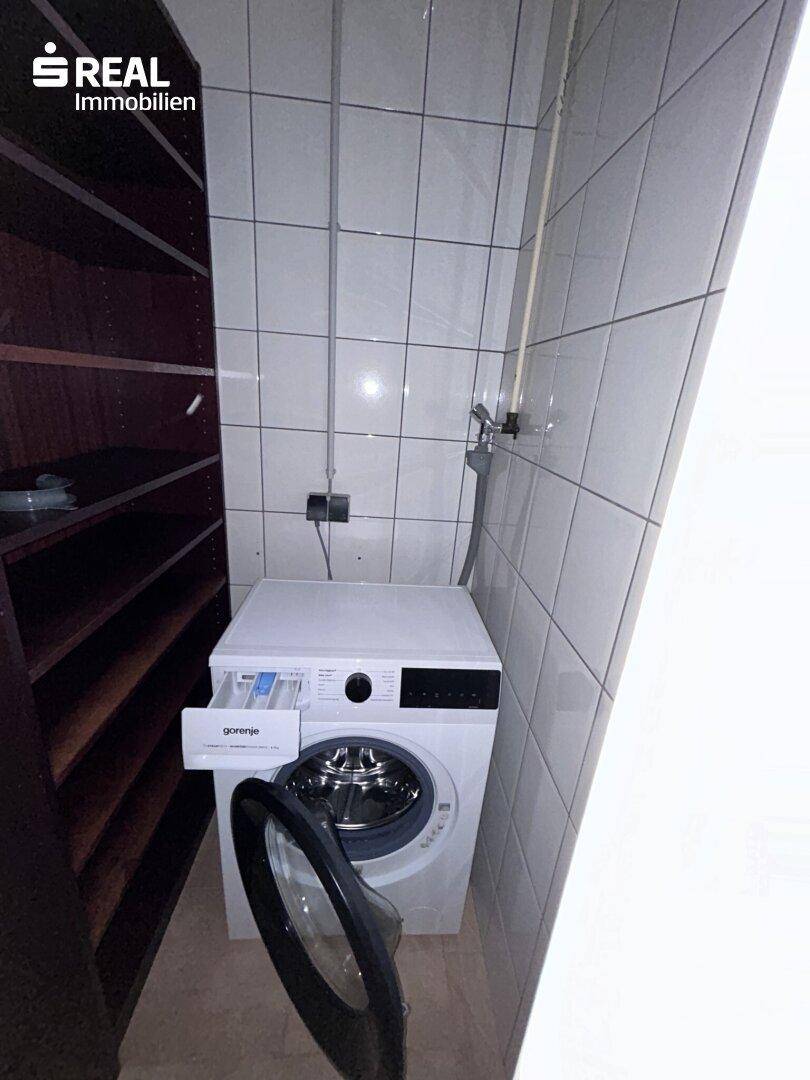 Praktischer Hauswirtschaftsraum mit Waschmaschine und Regalen für zusätzlichen Stauraum.