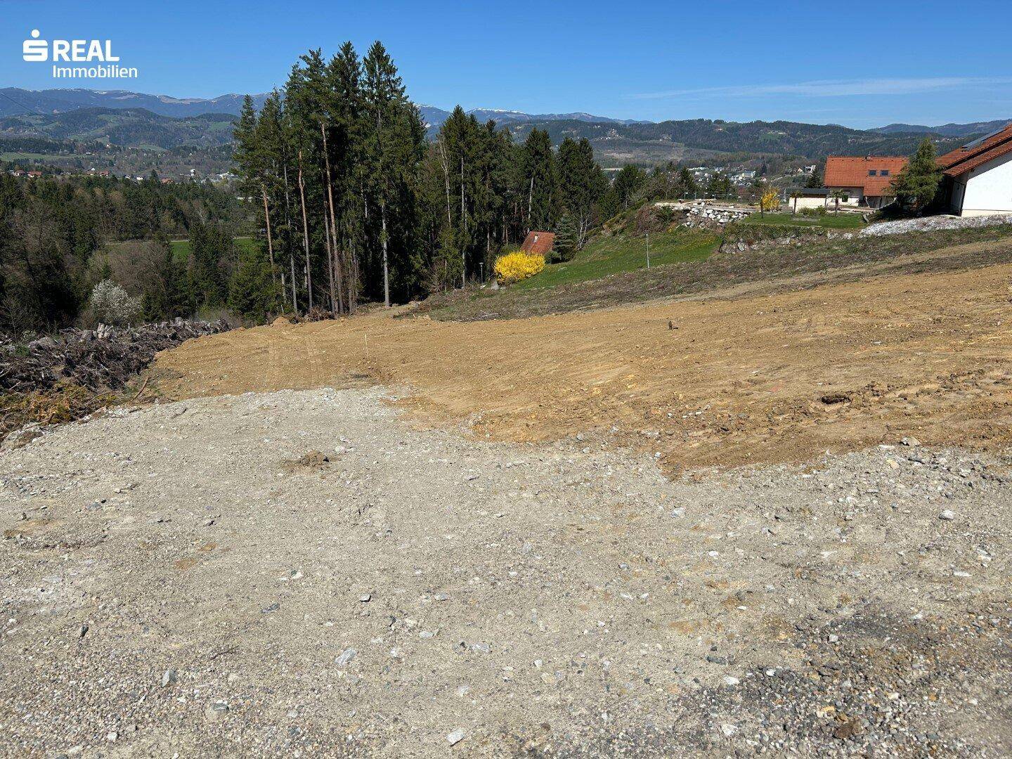 Blick über das Grundstück mit angrenzendem Wald und weitem Panorama.