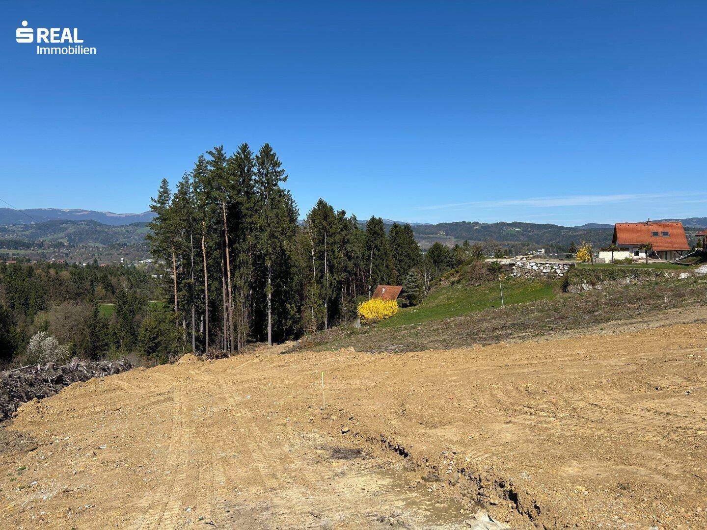 Großes Baugrundstück mit freiem Blick auf die umliegenden Wälder und die Bergkette.