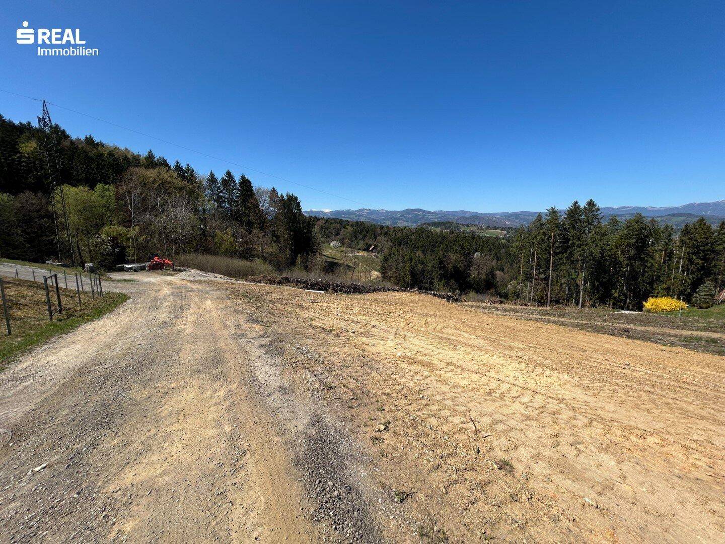 Zufahrtsweg zum Grundstück mit weitem Blick über die bewaldete Hügellandschaft.
