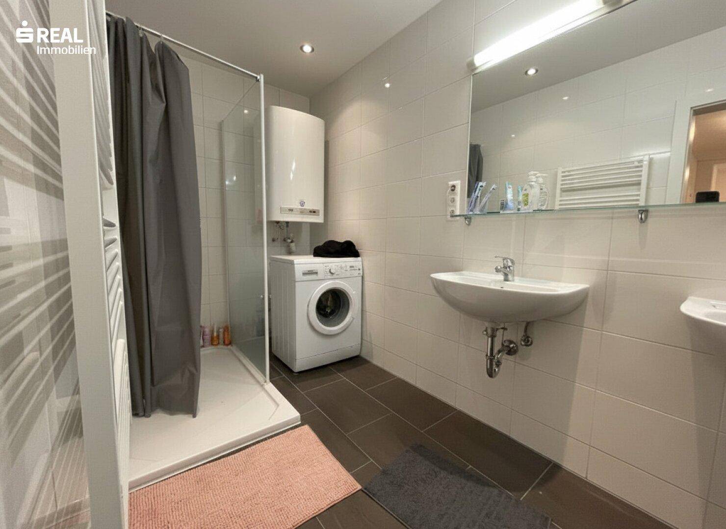 Modernes Badezimmer mit Dusche, Waschmaschine und beheiztem Handtuchhalter.