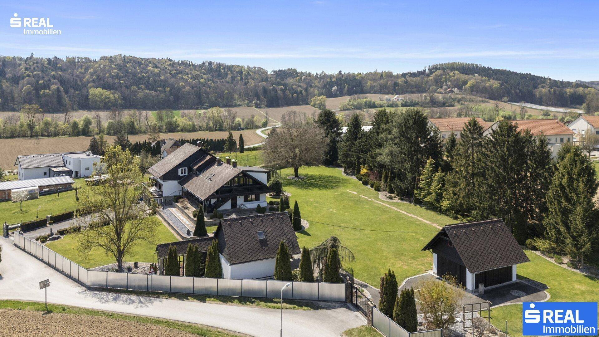 Panoramablick auf das weitläufige Grundstück mit angrenzenden Feldern und bewaldeten Hügeln.