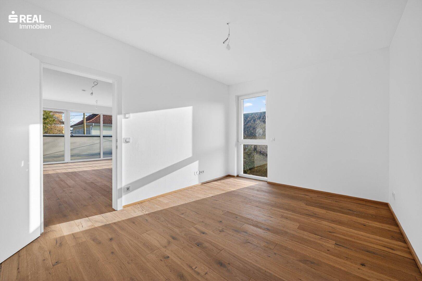 Geräumiger Raum mit Parkettboden und offener Verbindung zu einem weiteren Zimmer, vielseitig nutzbar.