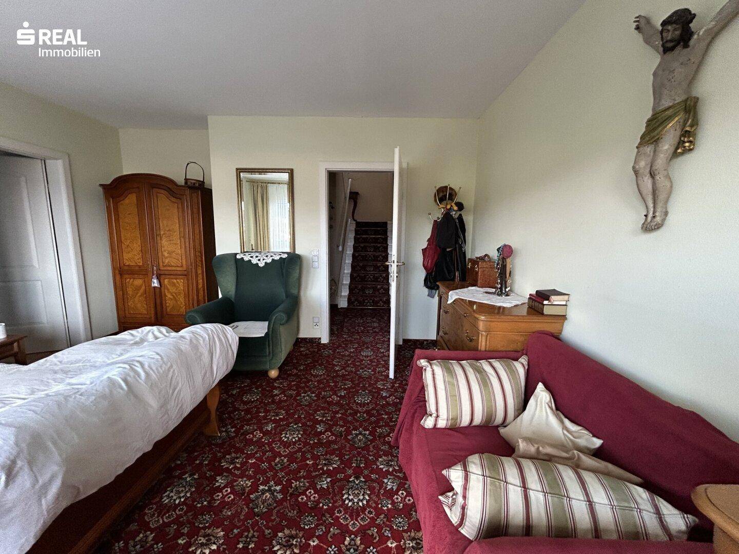 Schlafzimmer mit Teppichboden, traditionellen Möbeln und Zugang zum Flur.