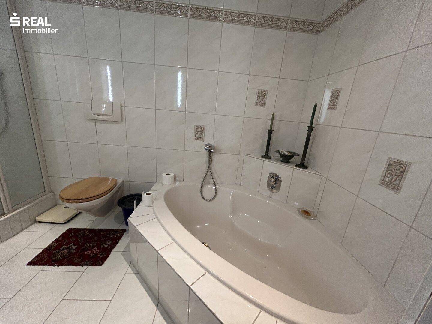 Badezimmer mit Eckbadewanne, WC und weißen Fliesen.