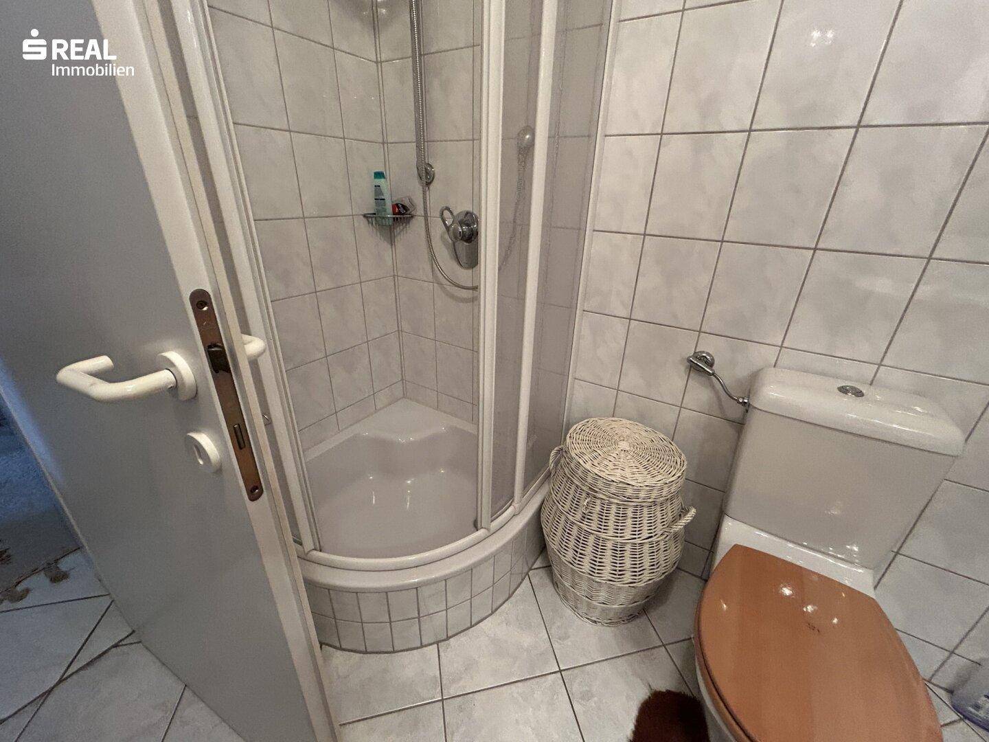 Badezimmer mit Duschkabine, WC und weißen Fliesen.