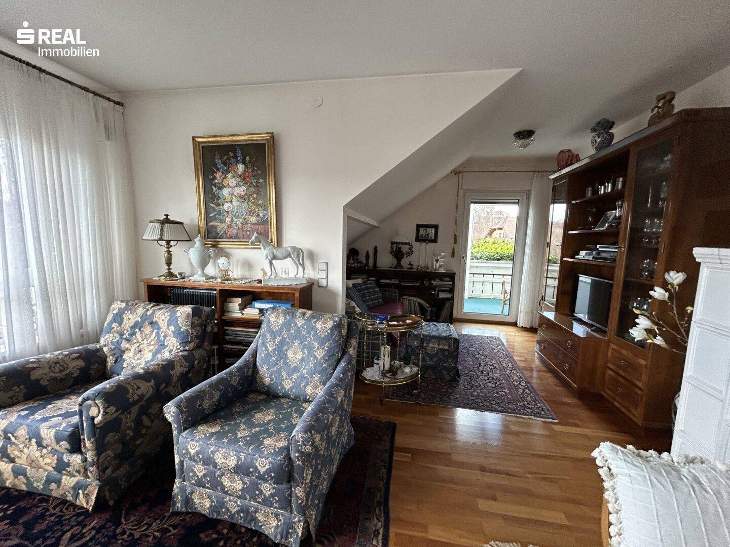 Gemütliches Wohnzimmer mit Holzboden, bequemen Sesseln und Zugang zum Balkon.