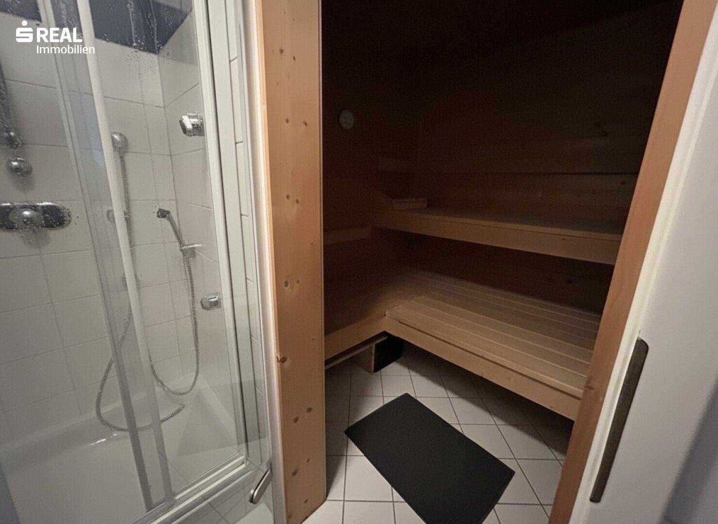 Badezimmer mit Duschkabine und integrierter Holzsauna.