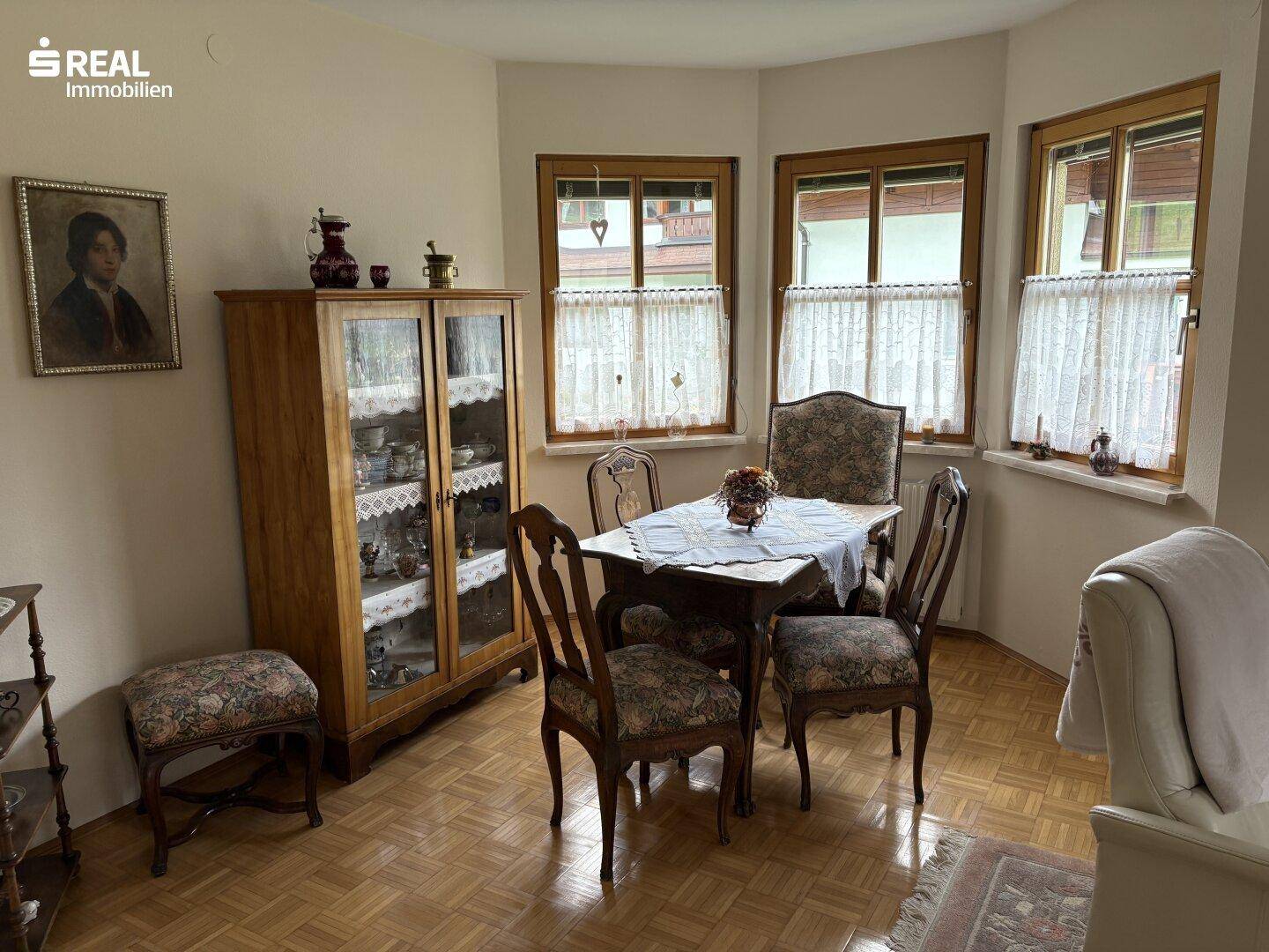 Essbereich mit Holzschrank, Esstisch und Fenstern mit Blick auf die Umgebung.