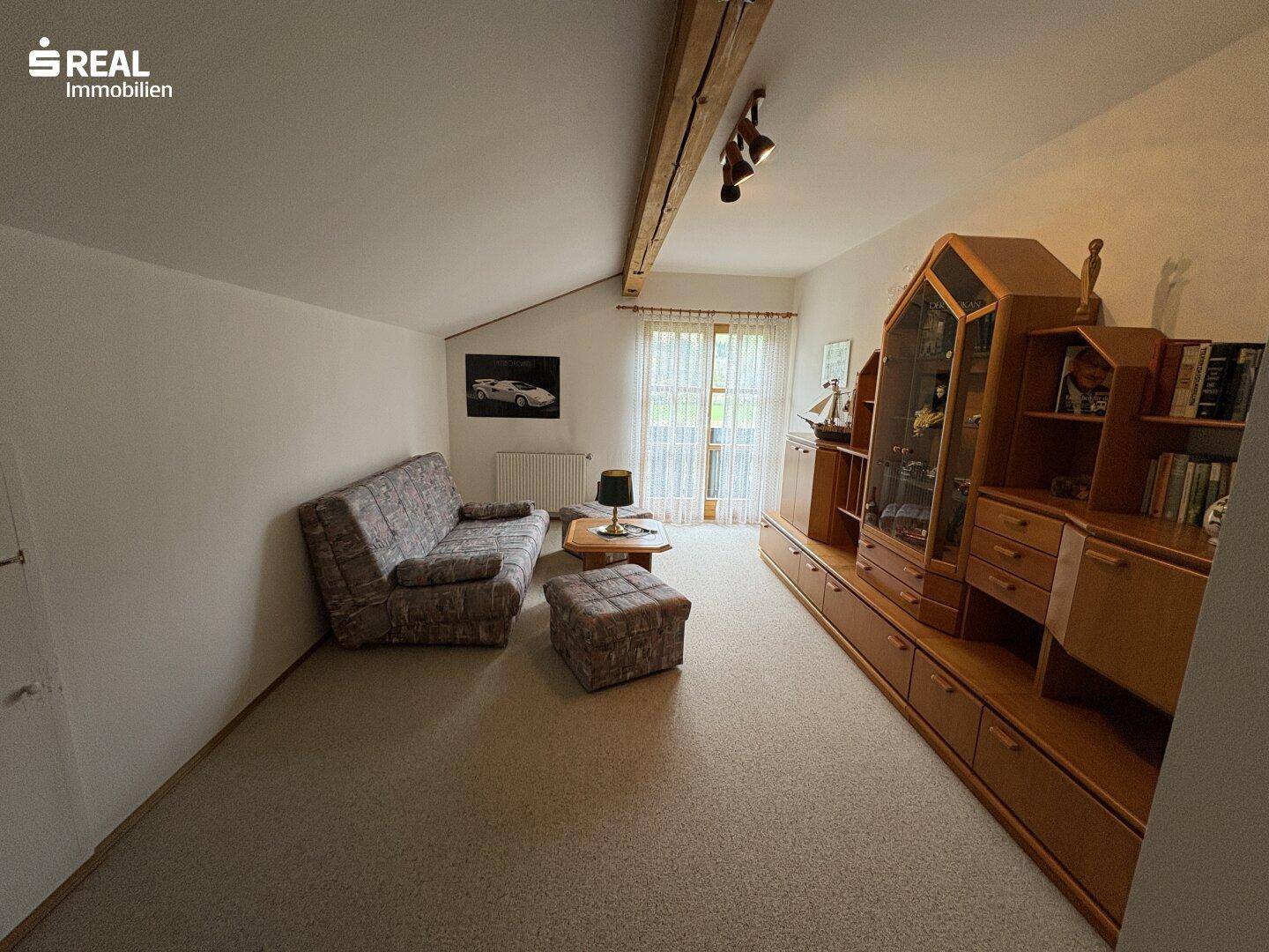 Gemütliches Schlafzimmer im Dachgeschoss mit Teppichboden, Dachschräge und Holzbalken.