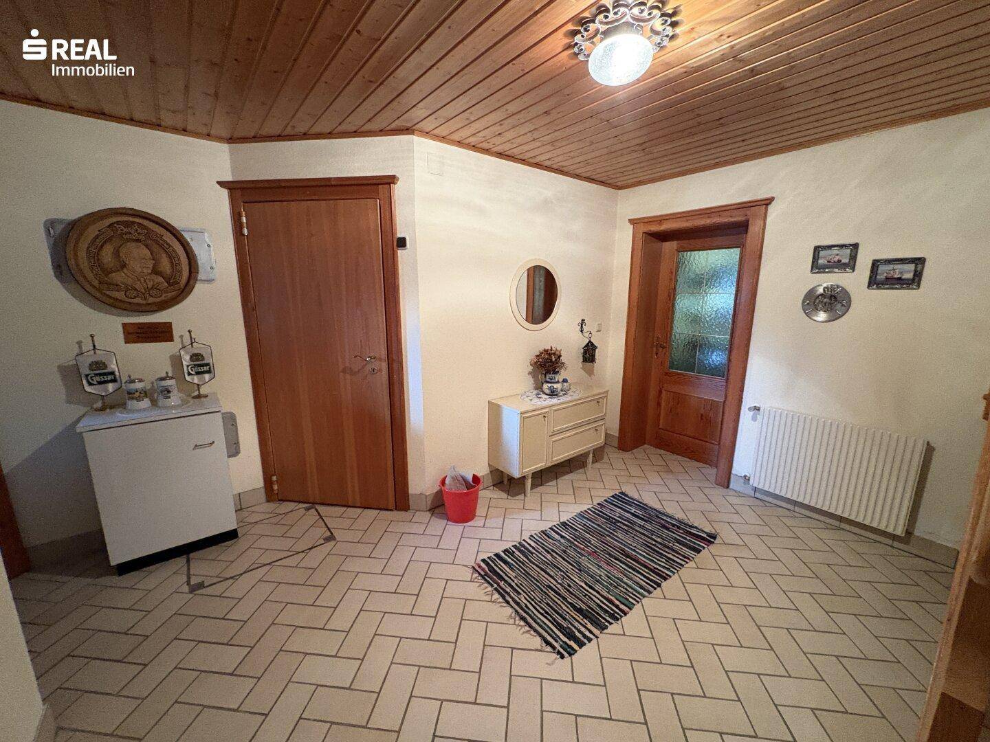 Heller Flur mit Fliesenboden, Holzdecke und traditionellen Dekorationen.