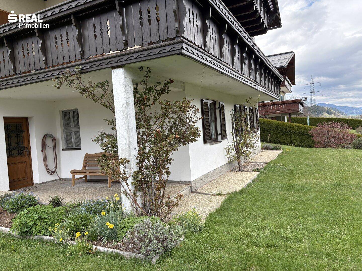 Kleiner Gartenbereich neben dem Haus mit Sitzbank und Blumenbeeten.