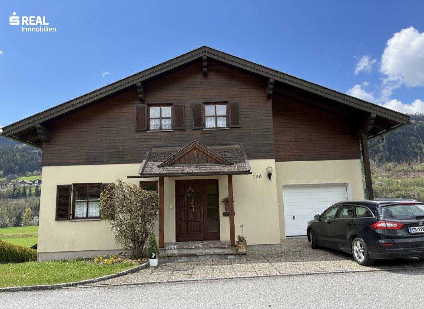 Vorderansicht des Hauses mit Eingangsbereich, Garage und gepflasterter Auffahrt.