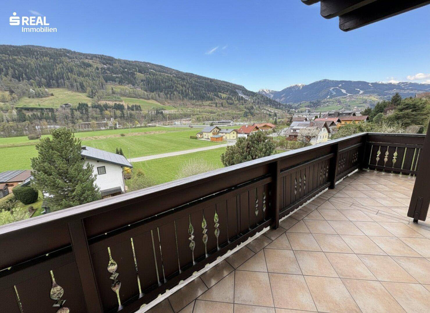 Großer Balkon mit Fliesenboden und weitem Blick auf die Berge und das Tal.